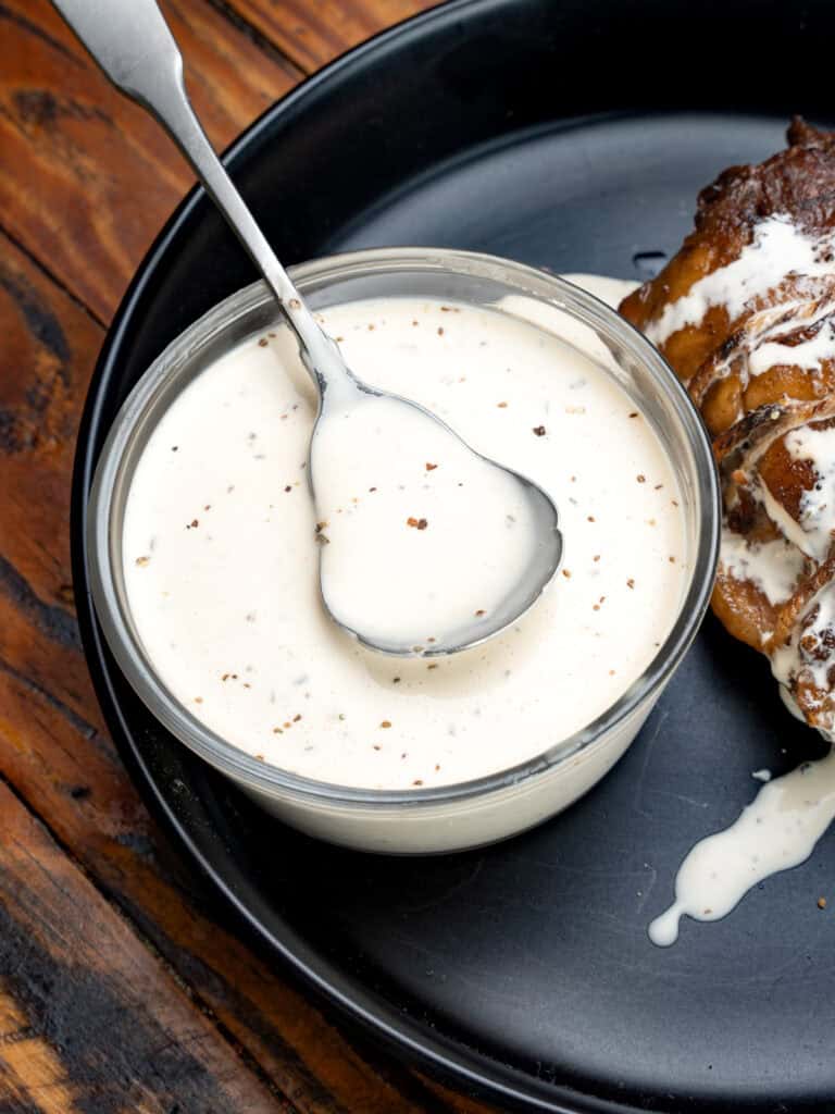 Alabama white sauce on a black plate with pork belly.