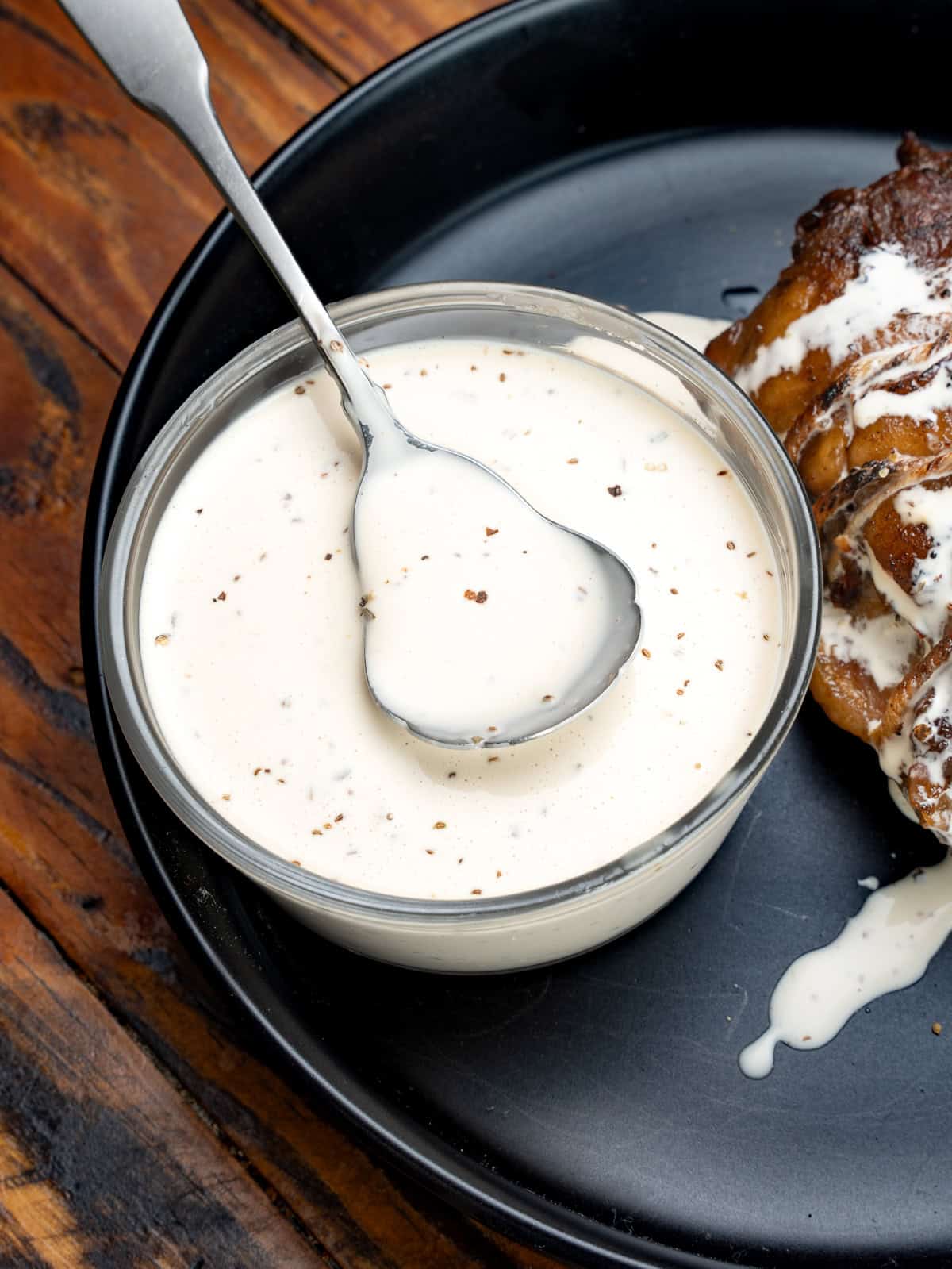Alabama white sauce on a black plate with pork belly.