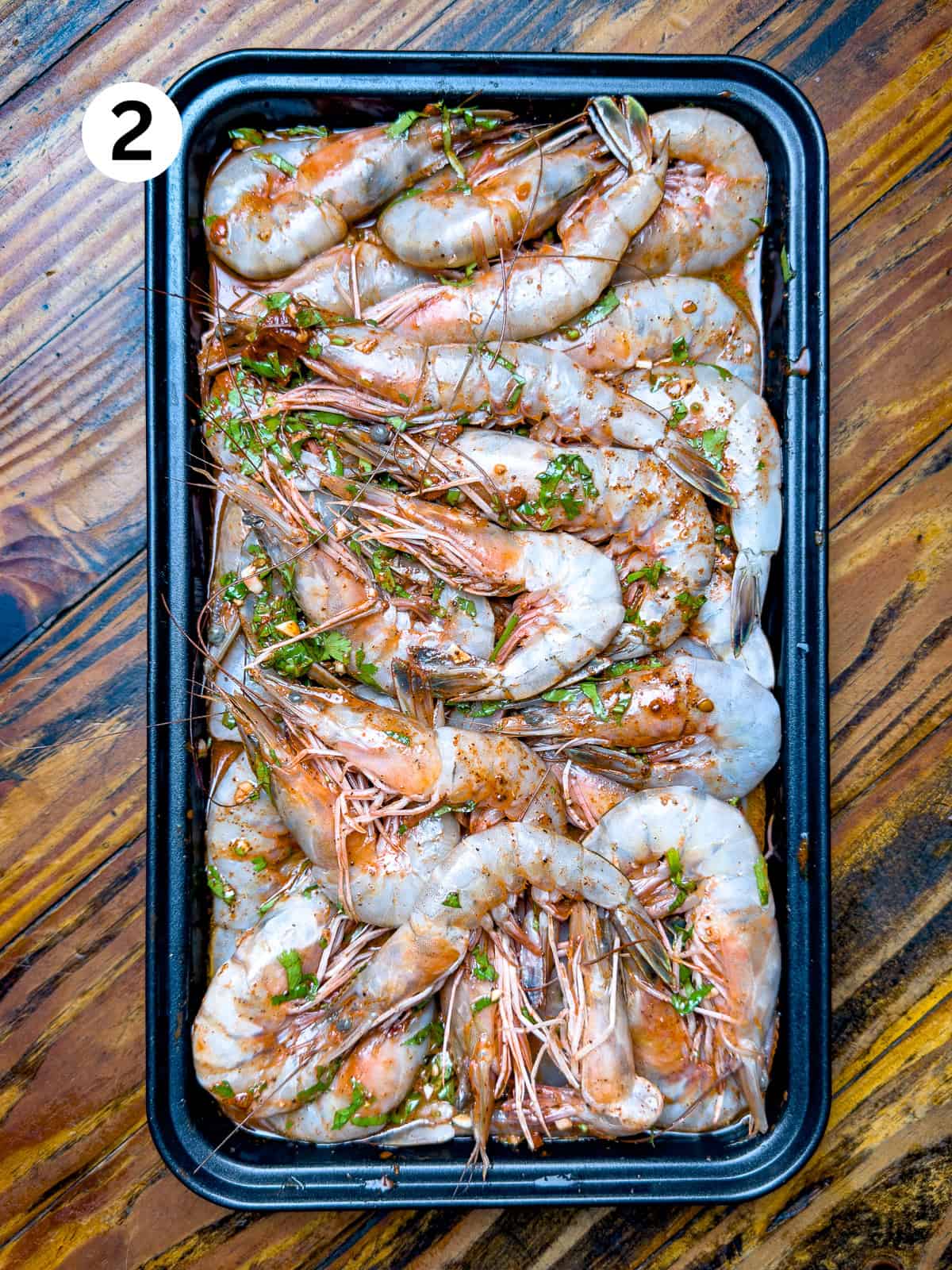 Shrimp marinating in a citrus marinade sitting on a wooden table.