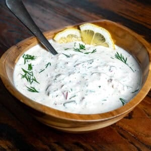Homemade tartar sauce in a wooden bowl with lemons.