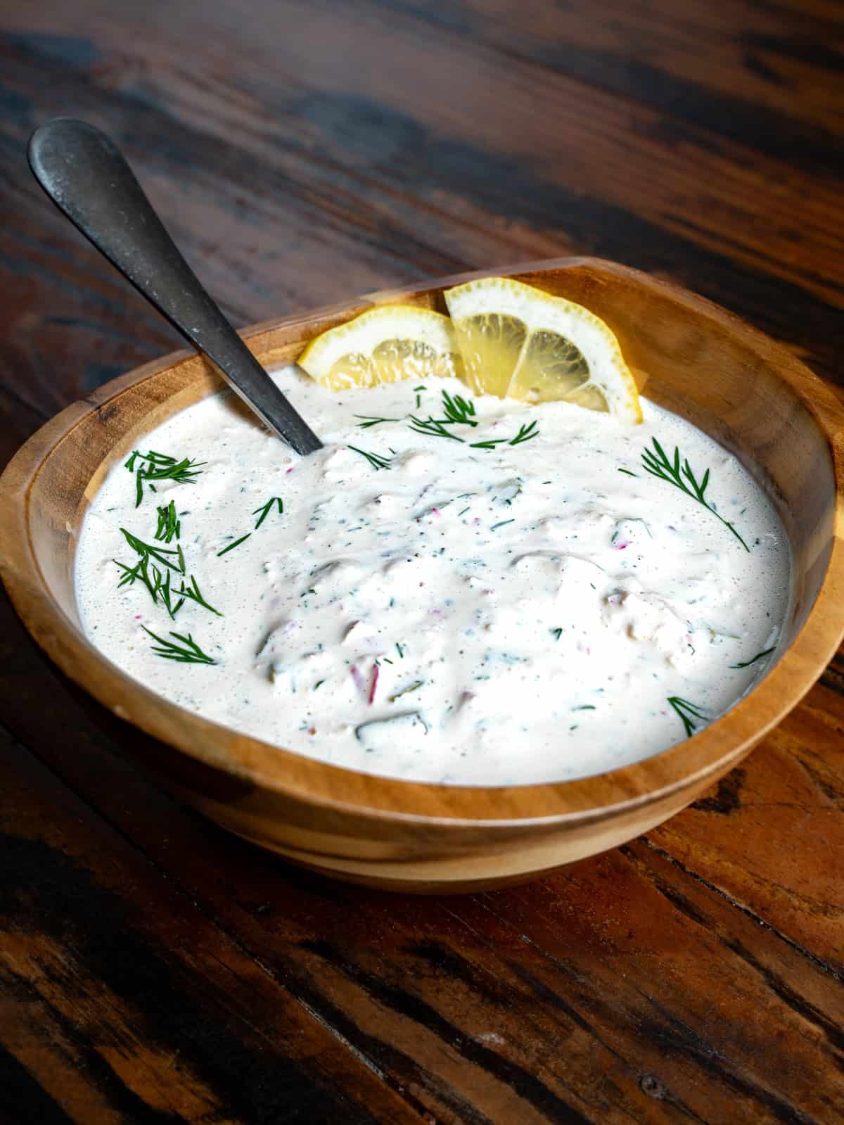 Tartar sauce in a wooden bowl with lemons.