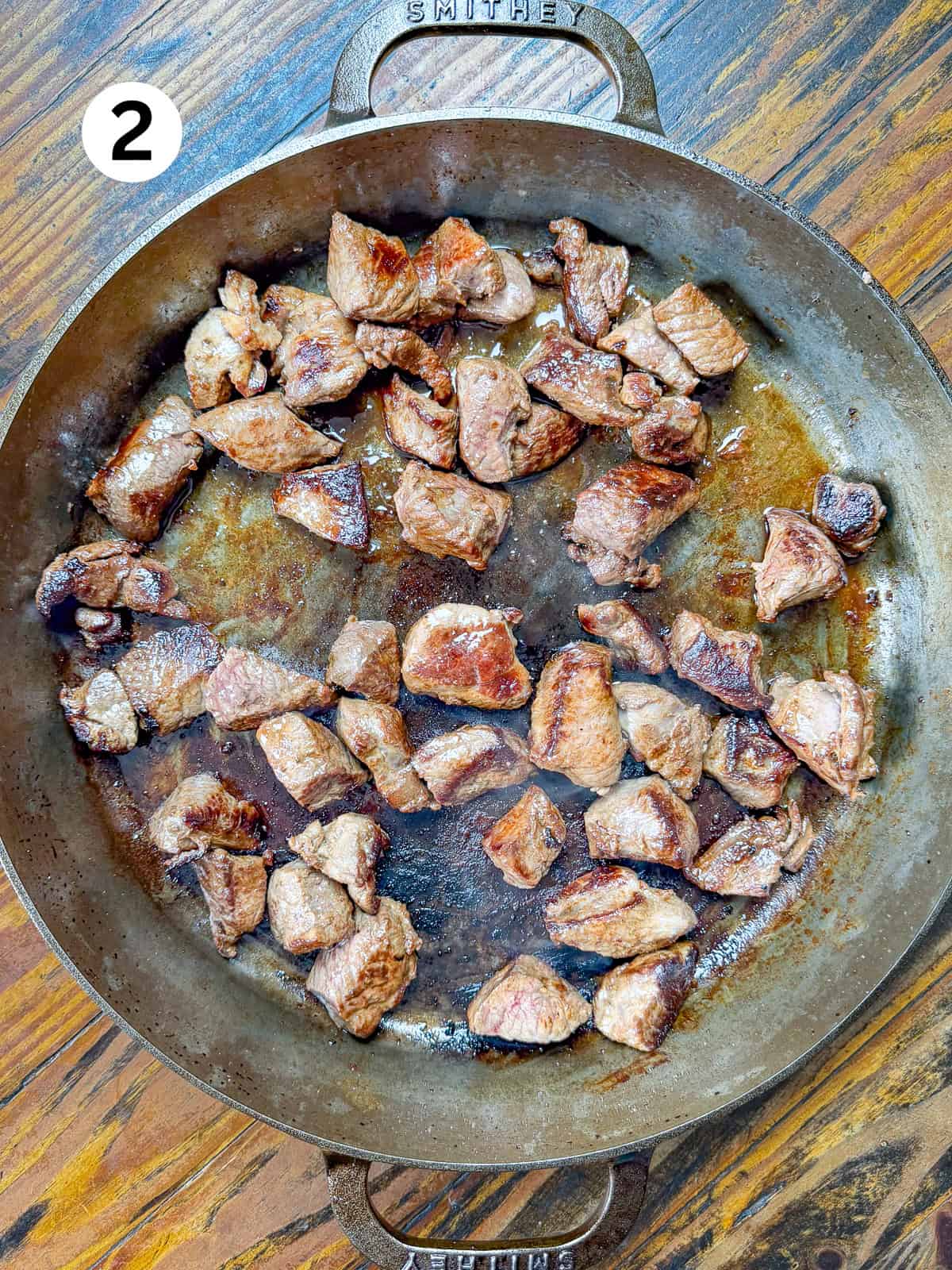 Seared venison stew meat in a cast iron pan.