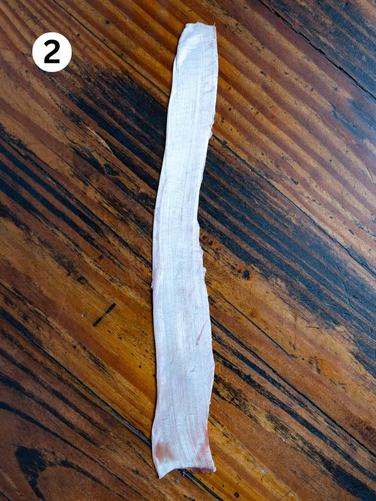 Silver skin trim from a venison backstrap on a wooden table.