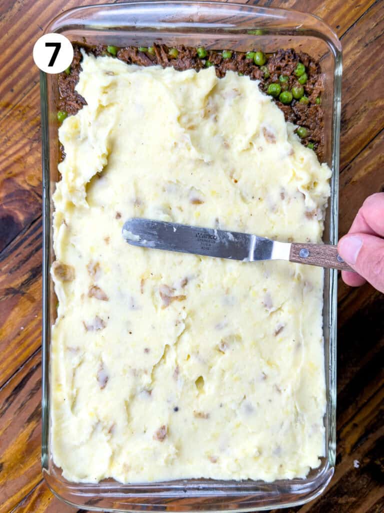 Spreading mashed potatoes over venison with an offset spatula