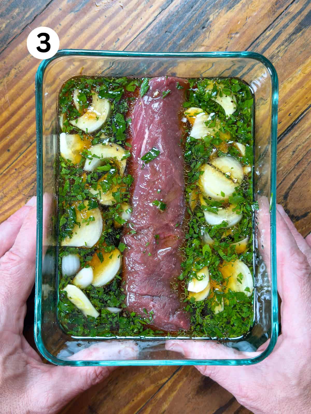Thai-Fish-Sauce-Dressing Venison backstrap marinating in a glass dish on a wooden table.