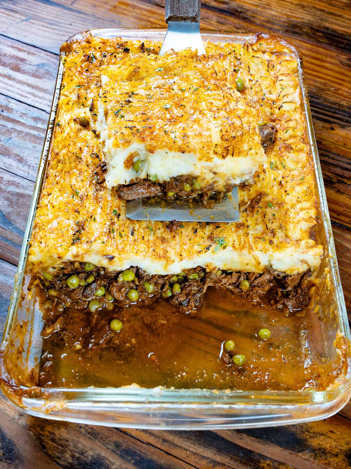 Venison shepherd's pie in a baking dish on a wooden table.