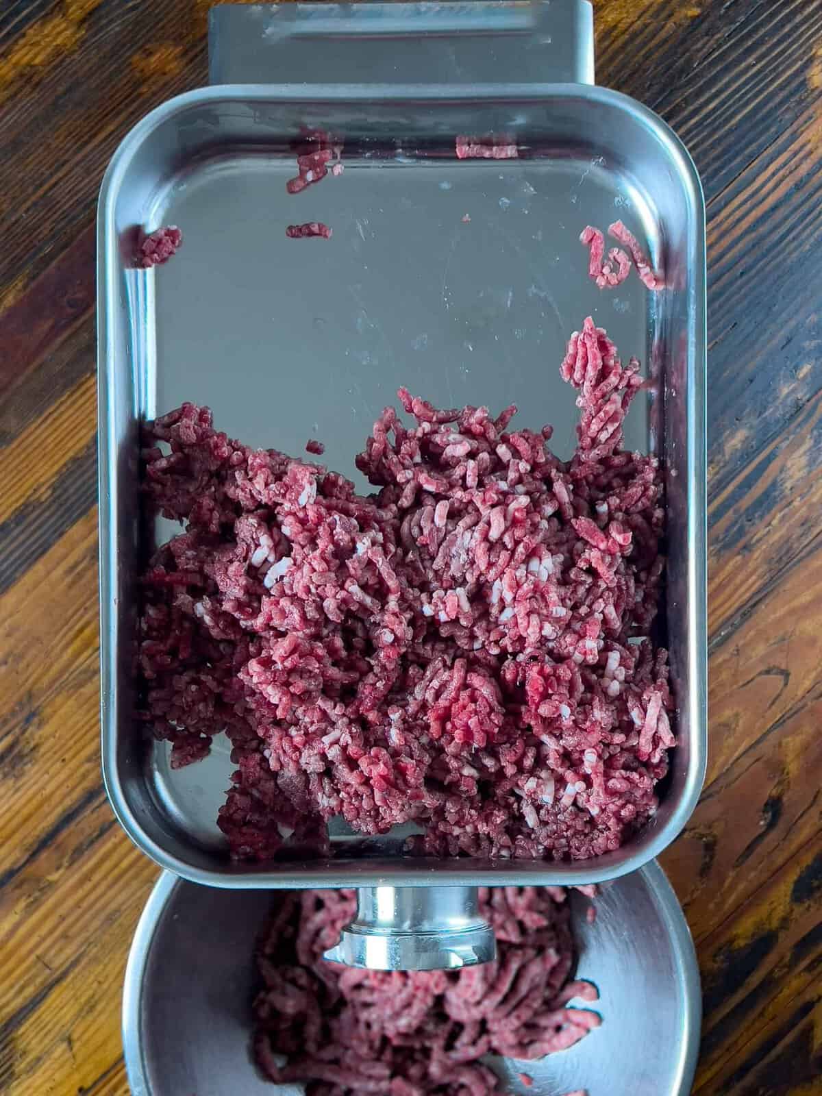 Ground venison resting in a grinder pan.