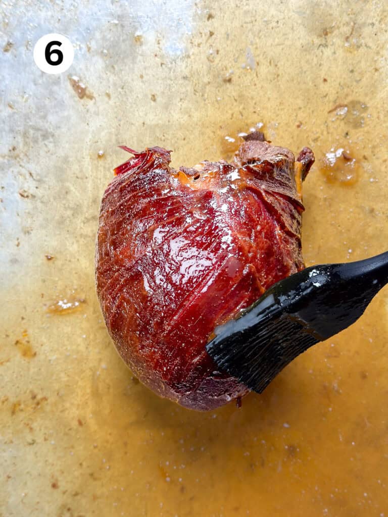 Glazing a venison roast with a black brush.