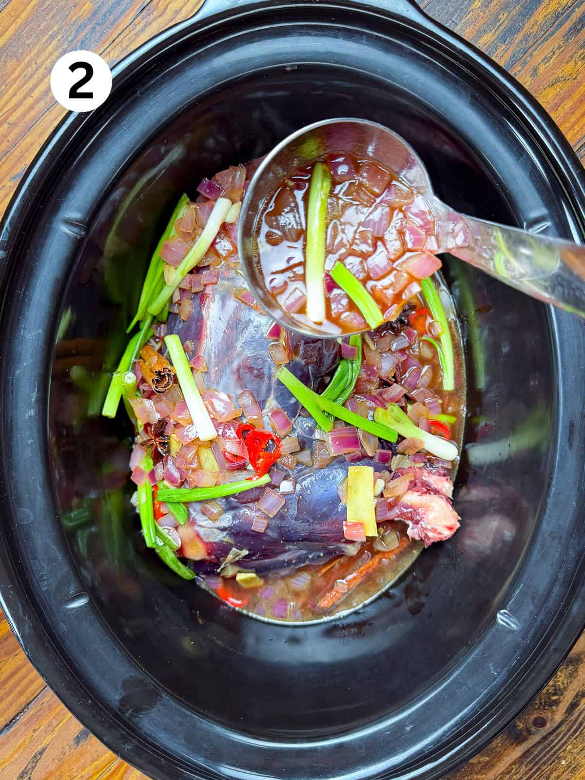 Pouring cooking liquid over a venison roast in slow cooker.