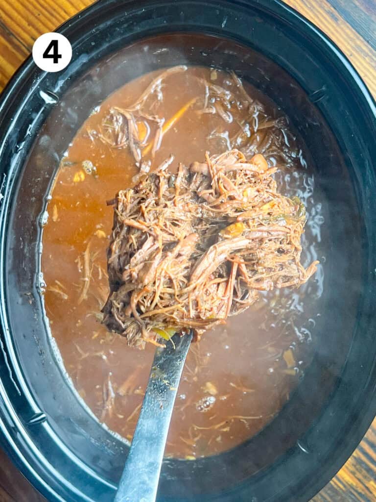 Shredded venison roast in a silver spoon.