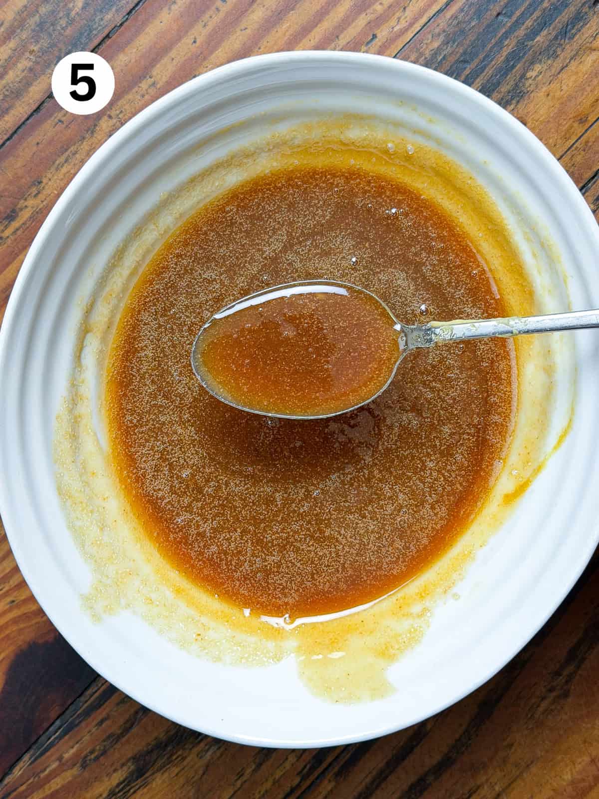 Glaze for smoked venison roast in a white bowl with a spoon.