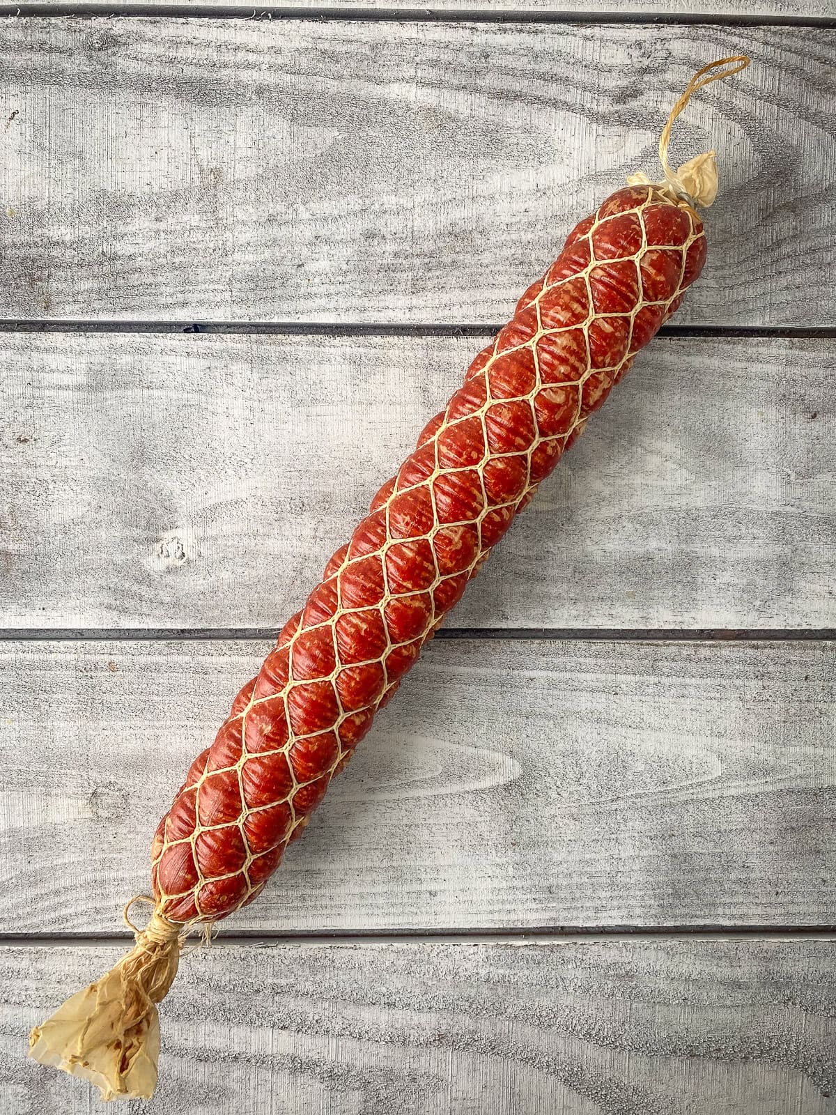 Venison summer sausage in a honeycomb casing on a wooden table.